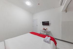 um quarto branco com uma cama e uma televisão em RedDoorz Syariah near Alun Alun Ciledug Cirebon em Cirebon