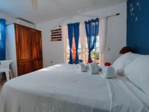 a bedroom with a large white bed with blue walls and windows at House Jardin Del Caribe in Las Terrenas