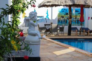 une statue d'une sirène assise sur une colonne à côté d'une piscine dans l'établissement Daniel Zanzibar Hotel, à Nungwi