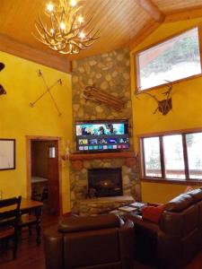 a living room with a stone fireplace and a tv at Snow Bear Breckenridge 4 in Taos Ski Valley