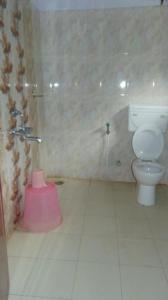 a bathroom with a toilet and a pink bucket at Shree Raksha Homestay in Gonikoppal