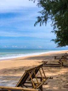 two picnic tables on a beach with the ocean at Lanta L.D. Beach Bungalow in Ko Lanta