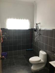 a bathroom with a white toilet and a window at Bendang Homes - Sekinchan Homestay in Kampong Sungai Leman