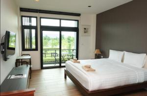 a bedroom with a large white bed and a balcony at Ravin Home ราวินโฮม in Nakhon Nayok