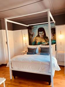 a white canopy bed with a painting of a woman at Cellar In Town in Robertson
