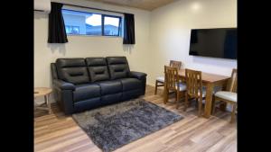 a living room with a black leather couch and a table at Country Retreats On Ranzau 4 in Hope