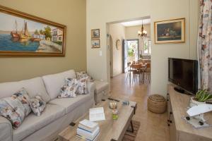 uma sala de estar com um sofá e uma televisão em Ruby's summer house with spacious garden and free parking em Gavrio