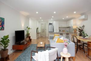 uma sala de estar com um sofá branco e uma cozinha em Huge 3 Bed Camperdown Garden Apt w Parking Aircon em Sydney
