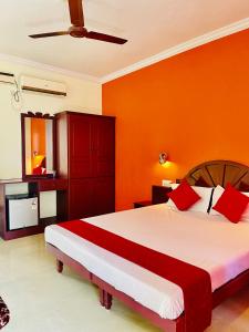 a bedroom with orange walls and a bed with red pillows at Moon Valley Cottage in Kovalam