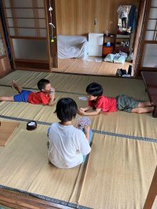 three children laying on the floor in a room at 古民家HAKKOU kibi 