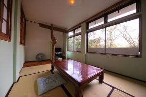Cette chambre dispose d'une table en bois et de deux fenêtres. dans l'établissement Nagahigawa, à Miyazaki