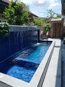 a swimming pool with a waterfall in a backyard at Rumah Tamu Firdaus in Marang