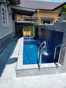 a swimming pool with a fountain in a yard at Rumah Tamu Firdaus in Marang