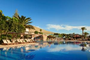 une grande piscine avec des chaises et des palmiers dans l'établissement Meliá Fuerteventura, à Costa Calma