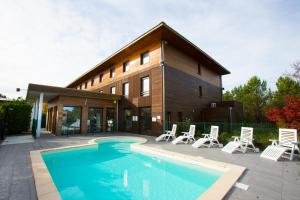 een huis met een zwembad en stoelen en een gebouw bij All Suites Le Teich – Bassin d’Arcachon in Le Teich