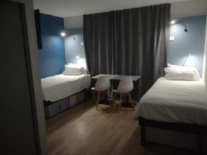 a hotel room with two beds and a table and chairs at Atao Residence- Rennes Sud in Vern-sur-Seiche