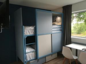 Habitación con armario azul, escritorio y ventana. en Atao Residence- Rennes Sud en Vern-sur-Seiche