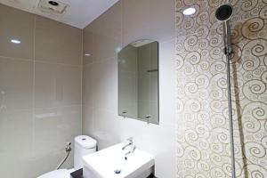 a bathroom with a toilet and a sink and a mirror at Paus Guest House Pekanbaru in Pekanbaru