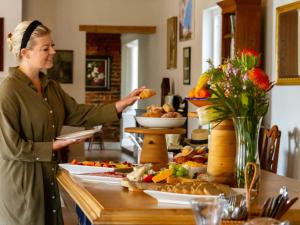 a woman standing in front of a table with food at Banhoek Corner Guesthouse in Stellenbosch