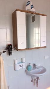 biała łazienka z umywalką i lustrem w obiekcie Apartment Monsberger w mieście Wolfsberg +7 zdjęć