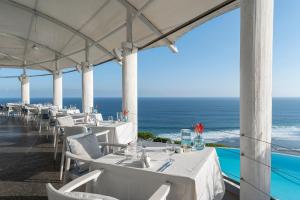 a restaurant with white tables and chairs and the ocean at Karma Kandara in Uluwatu