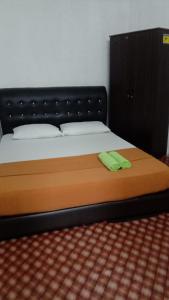 a bed with a black headboard and a green object on it at 7Rooms Hotel Budget in Bandar  Pusat Jengka