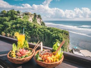 dos cestas de fruta en una mesa con vistas al océano en Mulia Manise The Bahari Villas Bali en Pacung