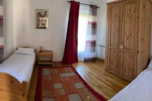 a bedroom with two beds and a window with red curtains at AMPAILLAN002 in Aosta