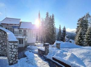 a building with snow on the ground in front of it at Vila Liliacul in Stana de Vale