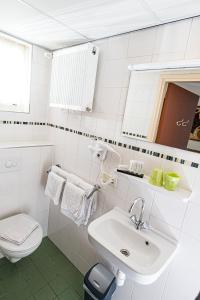 a white bathroom with a sink and a toilet at Pension Westerburen in Schiermonnikoog