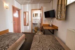 a room with two beds and a desk and a television at Pension Westerburen in Schiermonnikoog