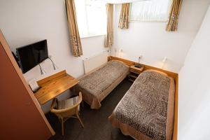 Zimmer mit 2 Betten, einem Schreibtisch und einem TV in der Unterkunft Pension Westerburen in Schiermonnikoog