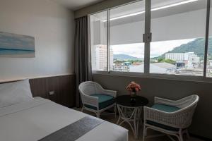 a hotel room with a bed and chairs and a window at Pearl Hotel - SHA Plus in Phuket