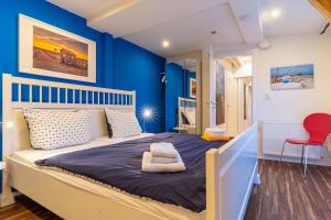 a blue bedroom with a bed and a red chair at null Haus Achtern Poggendiek, Whg Spatzennest, OG in Sankt Peter-Ording