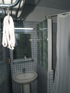 a blue tiled bathroom with a sink and a mirror at Champ de Mars B&B in Port Louis