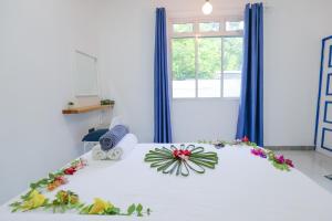 a bedroom with a white bed with flowers on it at Tropica Thoddoo Inn, Maldives in Thoddoo +10 photos