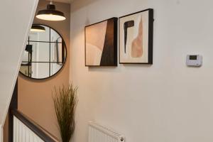 a hallway with two framed pictures and a mirror at Homebird Property - Mill Cottage in Leeds