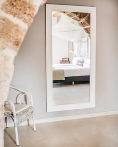 um espelho num quarto com uma cama e uma cadeira em Can Alemany em Santa Margarita de Mombúy