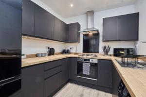 a kitchen with black cabinets and a stove top oven at Homebird Property - Salisbury House in Leeds