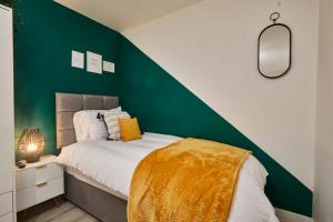 a bedroom with a green accent wall and a bed at Homebird Property - Salisbury House in Leeds