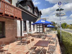a patio with tables and chairs and a blue umbrella at Land-gut-Hotel Zum alten Forsthaus - Aufladestation für Elektroautos in Hürtgenwald