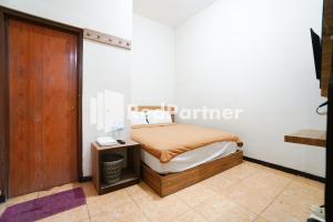 a small bedroom with a bed and a wooden door at Bright Residence near ITC Mangga Dua Mitra RedDoorz in Jakarta