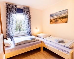 two beds in a room with a window at Frieslandstern - Ferienhof und Hotel in Wangerland