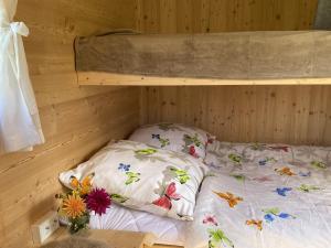 a bed in a wooden room with flowers on it at Schäferwagen Altensteig in Altensteig