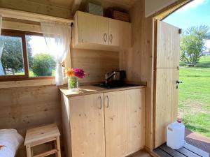 una pequeña cocina en una pequeña casa con ventana en Schäferwagen Altensteig, en Altensteig