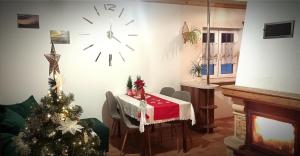 a room with a table with a christmas tree and a clock at Domek Regionalny- bliźniak in Baligród