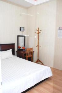 a bedroom with a bed and a desk with a cross on the wall at New Sleep in Dalat Hostel in Da Lat