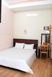Un dormitorio con una gran cama blanca y una mesa en New Sleep in Dalat Hostel en Dalat