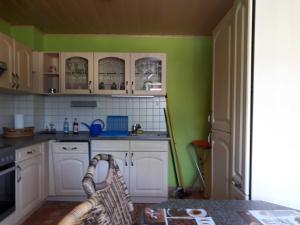 uma cozinha com paredes verdes e armários brancos em Ferienwohnung Krieger em Thurnau