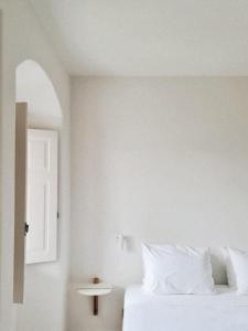 a white bedroom with a bed and a window at Ammothines Cycladic Suites in Naxos Chora